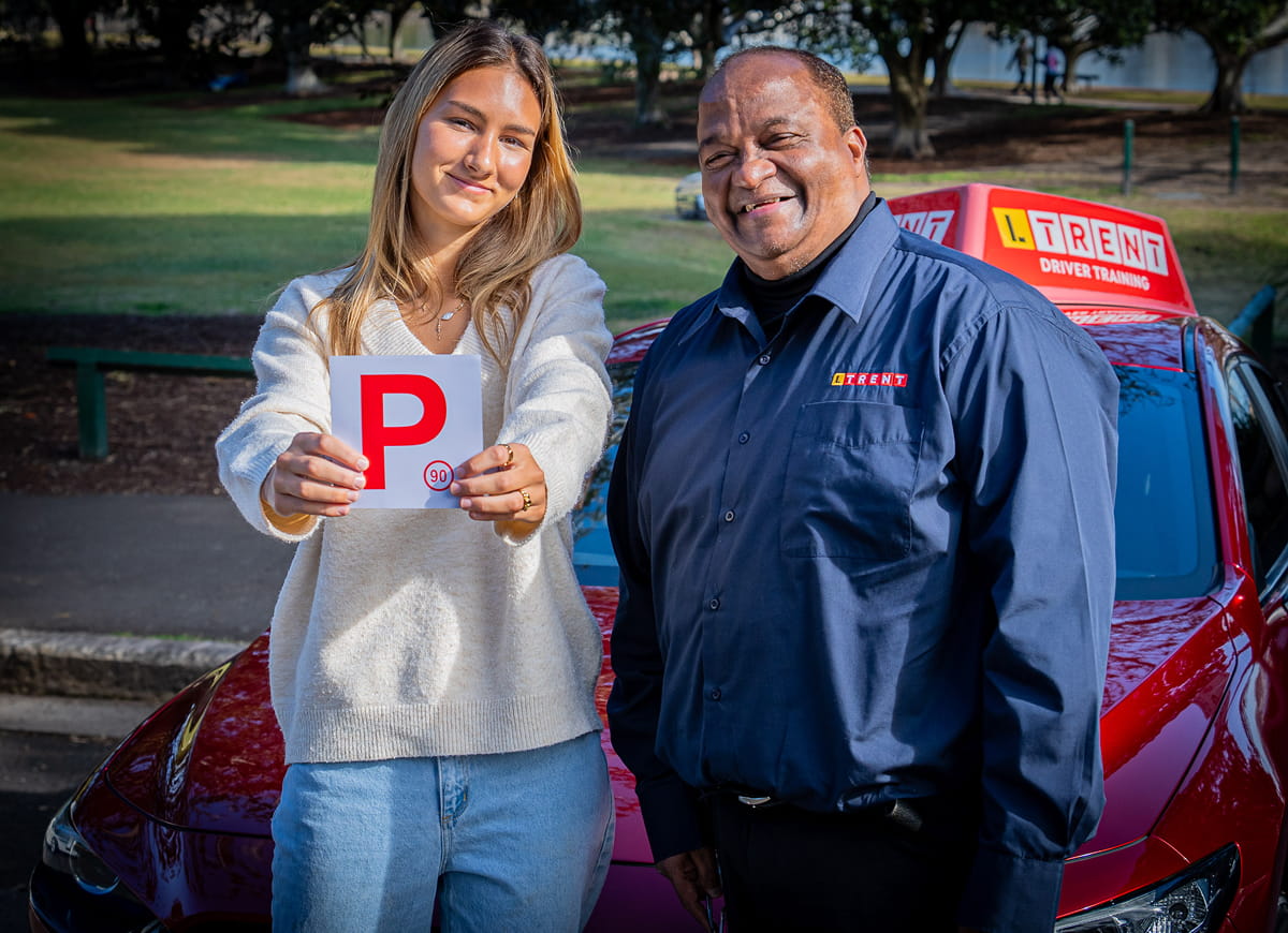 Adult learner driver holding NSW P plates besides LTrent driving instructor after building confidence through driving lessons in Australia