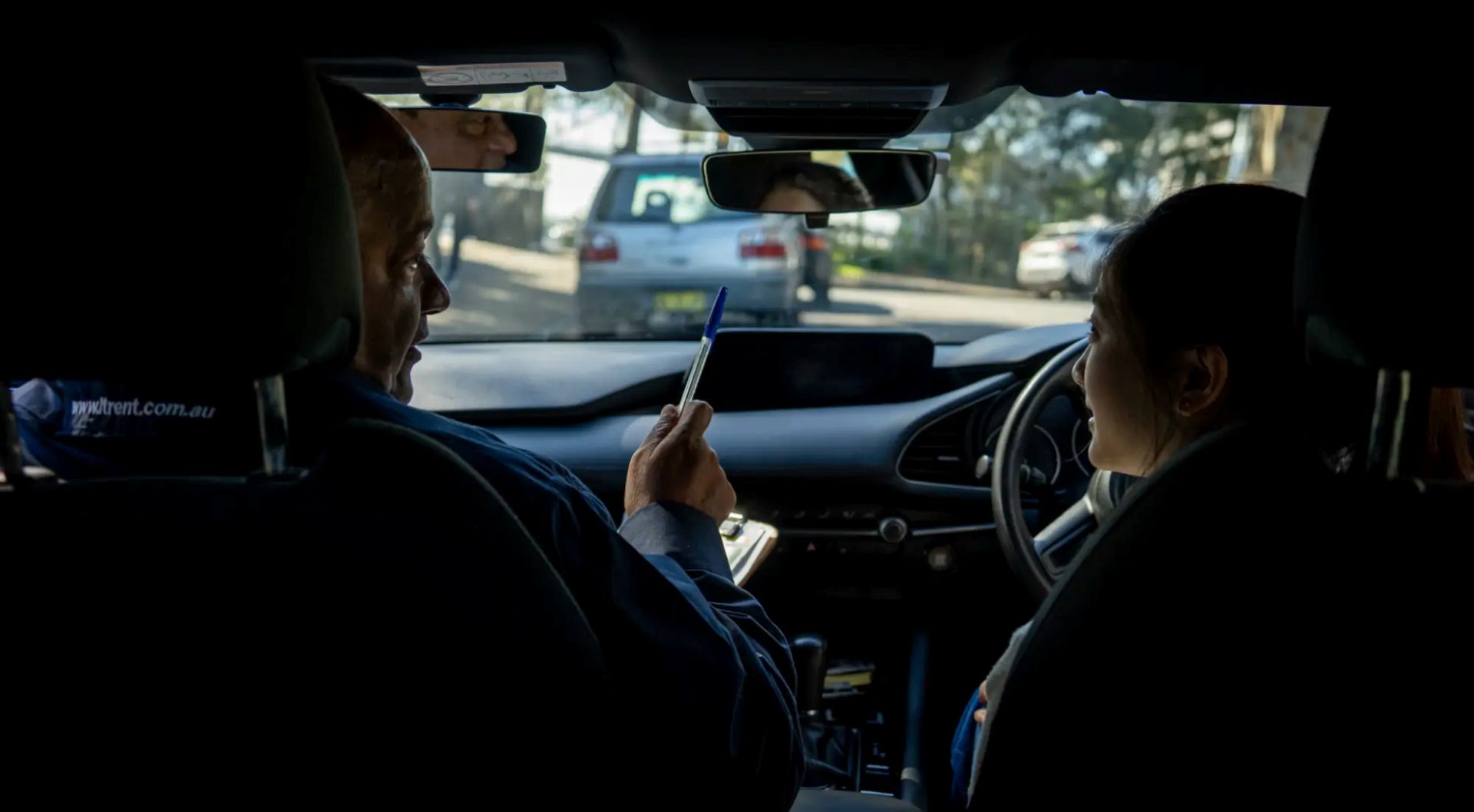 Driving instructor giving practical guidance to a learner driver during a driving lesson.