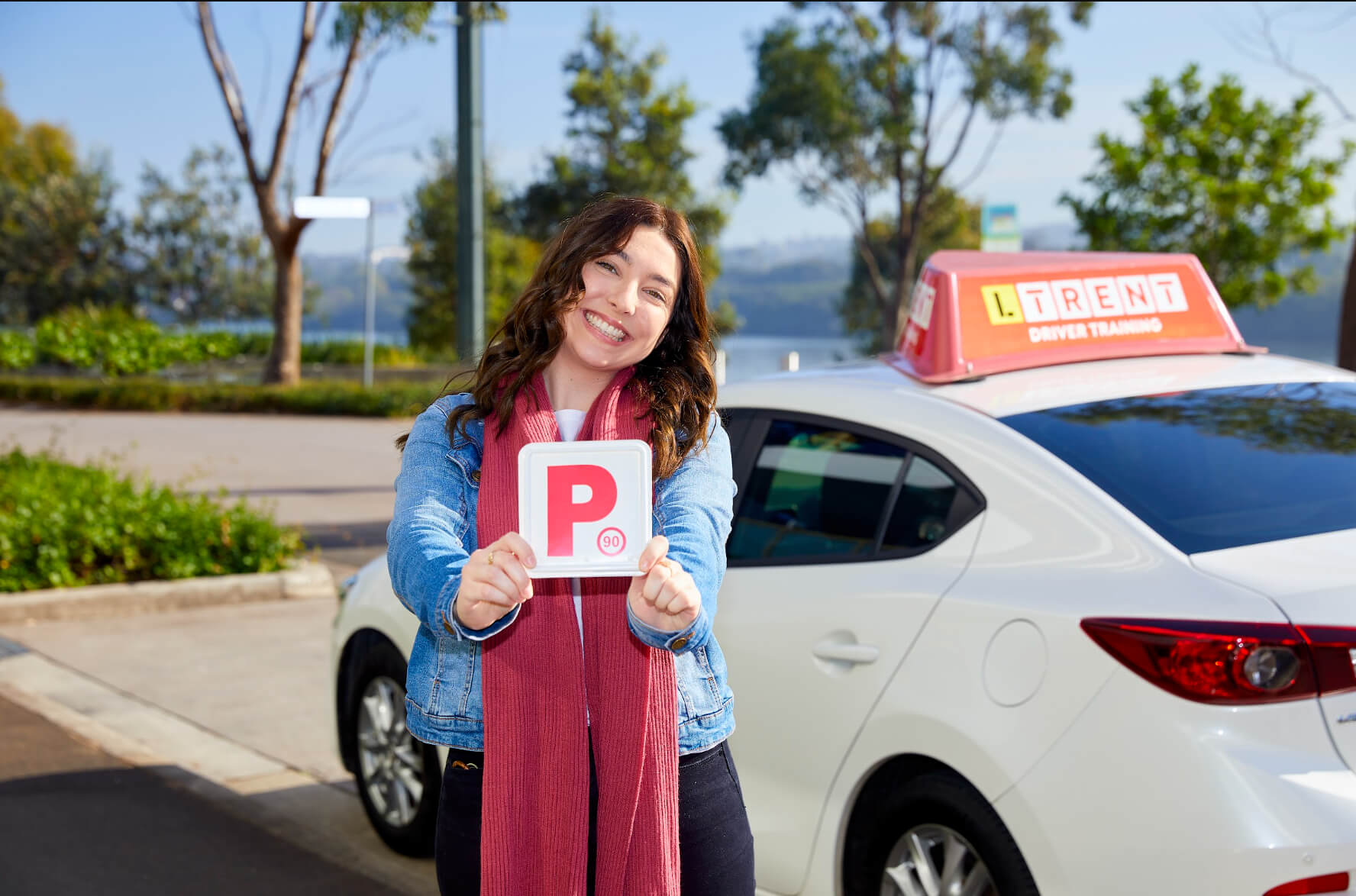Learner driver holding P plates after completing driving lessons and preparing for independent driving.