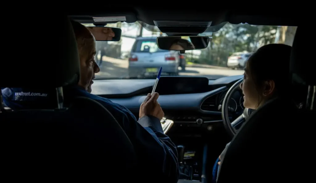 Driving instructor explaining a traffic situation to an adult learner during a practical driving lesson.