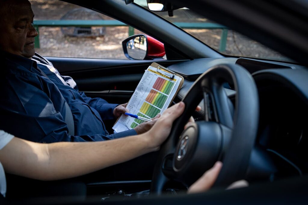 Driving lesson with an instructor assessing a learner's driving skills inside a car.