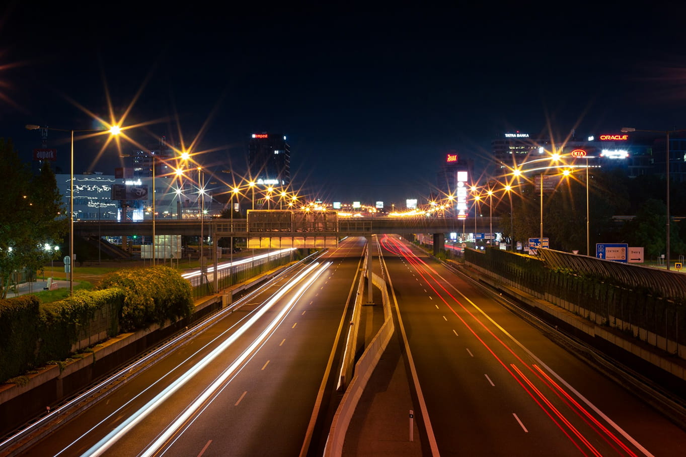 Multi-lane intersection at night with streetlights and vehicle headlights.